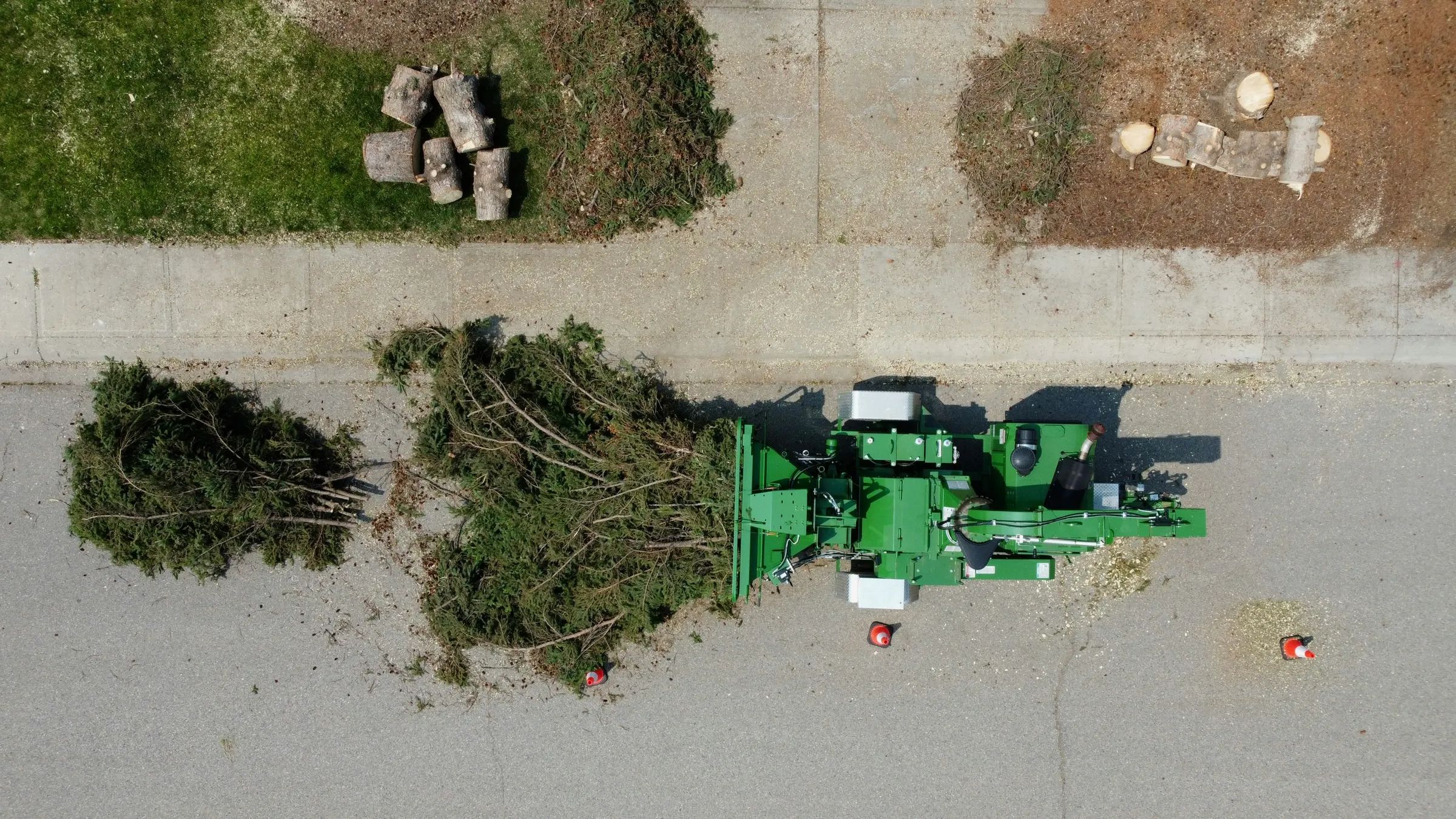 Aerial view of a tree crew feeding branches into a wood chipper on a residential street
