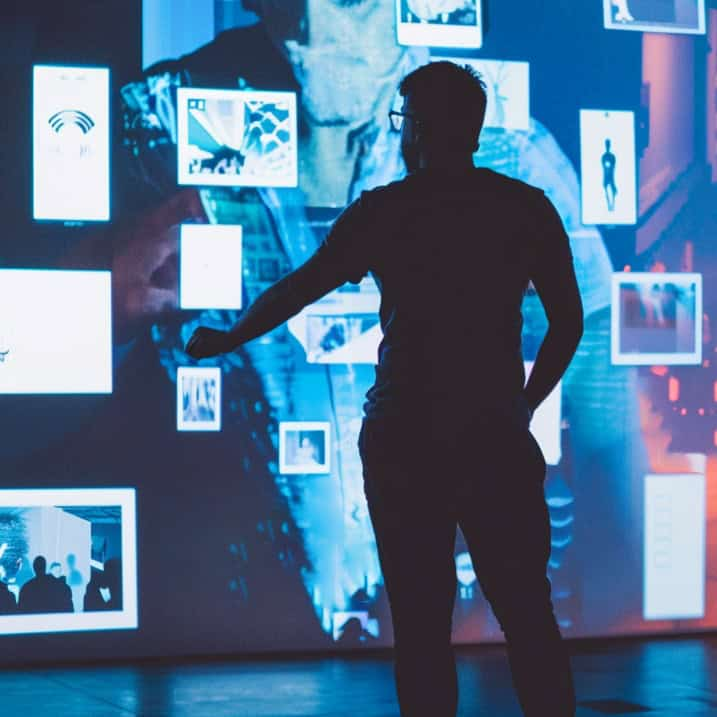 A person reviewing a wall of digital media in a high-tech gallery