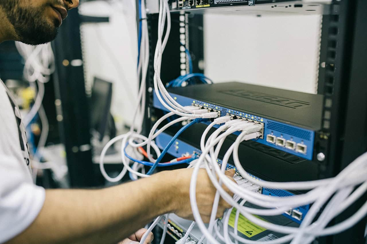A field engineer connecting cables in a network rack